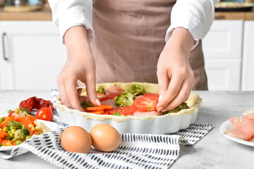 Obraz na płótnie Canvas Woman preparing chicken pot pie with vegetables at kitchen table, closeup