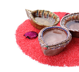 Diya lamps for Diwali with color powder on white background