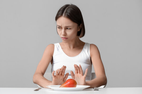 Young woman refusing from food on grey background. Anorexia concept