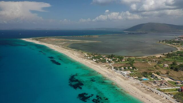 Aerial drone video of famous for water sports like kitesurfing sandy turquoise beach of Agios Ioannis with old abandoned windmills and lovely clouds, Lefkada island, Ionian, Greece