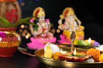 Clay Diya Deep Dia Lamp Lit in Pooja Thali With Flowers, Mithai, Agarbatti And Kalash In Front Of Maa Lakshmi And Bhagwan Ganesha Deva. Diwali Puja , New Year, Deepawali Or Shubh Deepavali