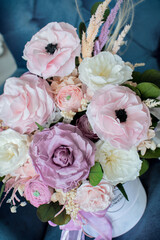 Cozy room, flowers in box on blue armchair. Preserved flowers bouquet closeup. Eternal, stabilized, forever rose flower.