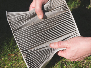 Dirty air filter for the cabin in the hands of man, close up. Changing the car air filter....