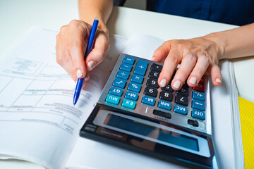 Close up of beautiful woman hands using calculator keyboard. Concept of accountant work. Financial...