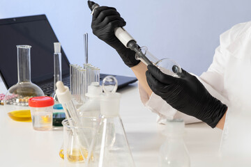 Pharmacology concept. Drug testing. Hands of a lab assistant with flask and pipette. Laboratory...