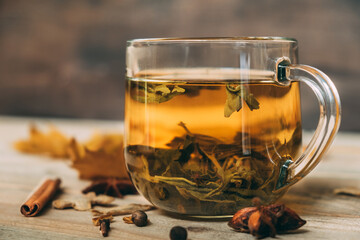 Green tea in a glass cup close-up. Against the backdrop of a cozy autumn background with autumn leaves and spices. Relaxing atmosphere.