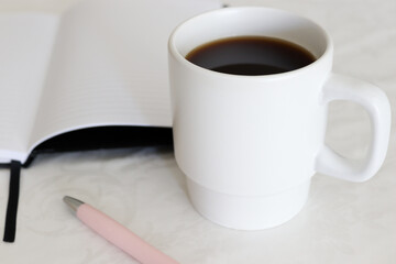 Closeup of cup of coffee on a table with a notebook in the background