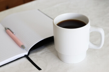 Cup of coffee, notebook and pen. White background