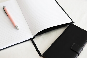 Pen on notebook and smart phone on a white background