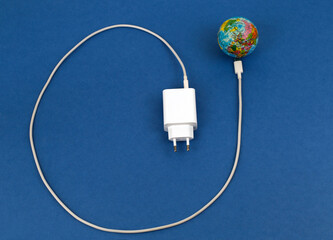 USB cable disconnected from the globe on a blue background. Energy crisis concept.