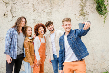 Happy young people taking selfie in the city - Multiracial group of friends is taking a photo looking at the camera