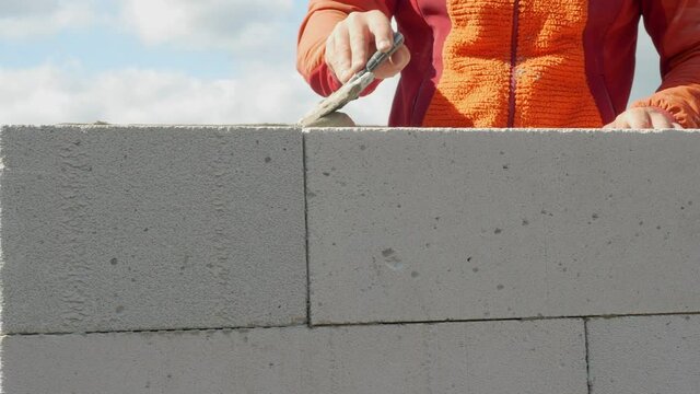 The builder works with a spatula. The man cements the building blocks. Home construction