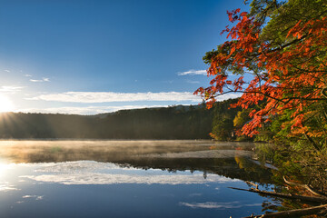 美しい紅葉の白駒池の湖面に反射する日の出