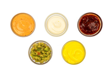 Bowls with Mexican cuisine sauces, guacamole, chili, raw, paprika on a white plate.