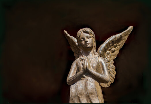 praying angel statue on black with copy space