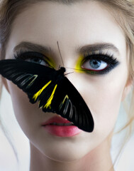 Beautiful young woman with perfect skin and bright yellow make up posing with butterfly on her...