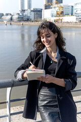 Fototapeta premium A young woman takes notes in a ring-bound notebook on the street