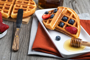 Waffles with berries and maple syrup on a wooden table.