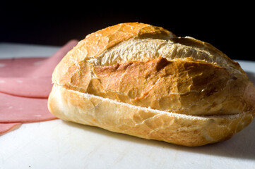 traditional bologna bread on a white board with black background, copy space and selective focus.