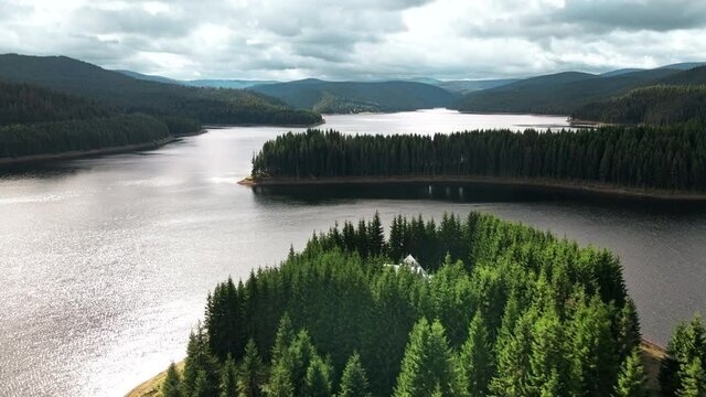 Aerial drone view of nature in Romania. Carpathian mountains, hills with lush forest, valley with Oasa lake