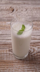 Turkish or Azerbaijan traditional Drink Ayran or Kefir with herbs and with mint in a glass on a wooden table front view. Fermented milk drink for diet. Copy space. the concept of healthy nutrition.