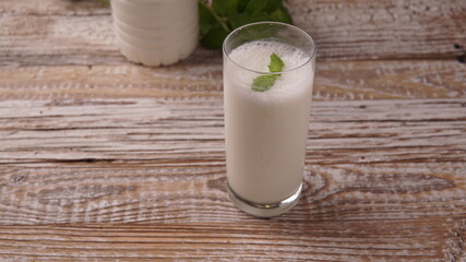 Turkish or Azerbaijan traditional Drink Ayran or Kefir with herbs and with mint in a glass on a wooden table front view. Fermented milk drink for diet. Copy space. the concept of healthy nutrition.