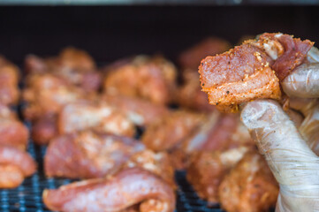 Pork being smoked on a barbecue grill with dark background and selective focus.