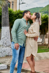 Young Latin male and female couple in love giving each other a kiss between 25 and 35 years old