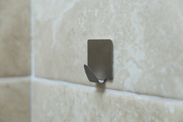 Metal hook for clothes on a tile. Wall hook for towels