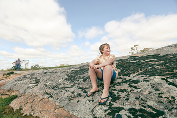 Happy caucasian boy sitting on large rock in National Park