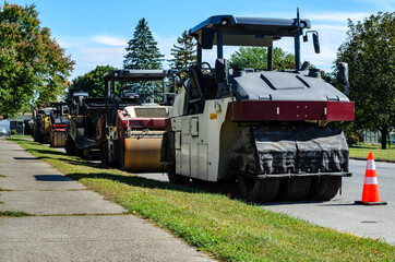Road construction machinery lined up along a residential street