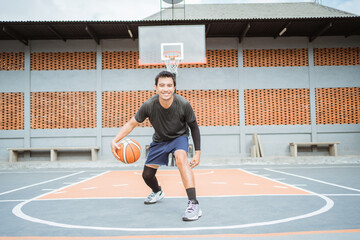 a basketball player performs a low dribble between the legs dribble with the ball while practicing...