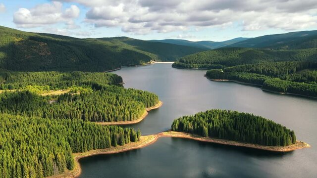Aerial drone view of nature in Romania. Carpathian mountains, hills with lush forest, valley with Oasa lake