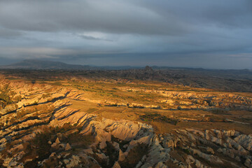  look from above at a yellow-brown rocky valley flooded with evening sun
