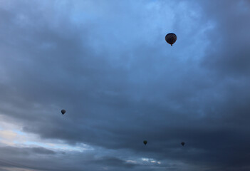 our small silhouettes of flying hot air balloons against the evening sky