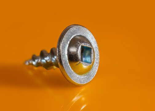Clos up shot of tiny metal self tap screw against yellow background created with multi photo focus stacking