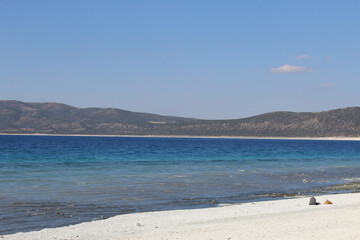Fototapeta na wymiar blue salt lake, view from the snow-white shore under a bright summer sky