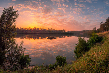 Fototapeta na wymiar Riverside Sunrise with Cloud Reflections