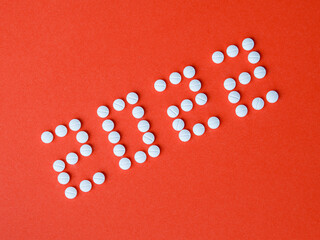 2022 Happy New Year banner for health care and medical concept. Number 2022 made from tablets on a red background in diagonal. View from above flat lay. Medical concept.