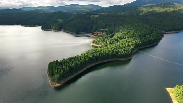 Aerial drone view of nature in Romania. Carpathian mountains, hills with lush forest, valley with Oasa lake