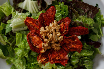 Horizontal image. Close-up of variety salad of lettuce, spinach, arugula, sun-dried tomatoes and walnuts.