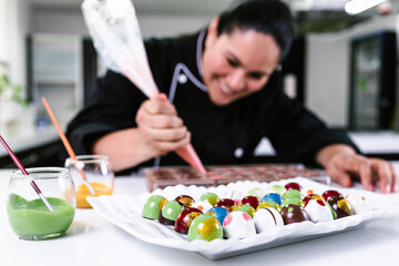 latin woman pastry chef wearing black uniform in process of preparing delicious sweets chocolates at kitchen in Mexico Latin America, mexican chocolate 