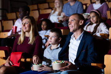 parents with children laughting at movie in cinema