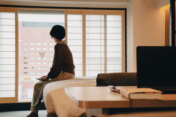 ショートヘアの女性が窓の外を眺めている