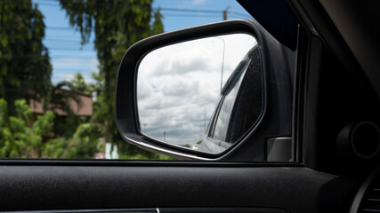 Fototapeta na wymiar Inside view of car can see mirror wing with glass. Look back in the mirror and see the side of the car, sky and clouds.