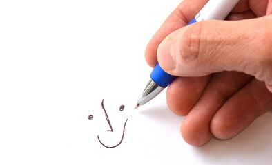 hand with pen drawing a smiley face