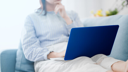ソファーでノートパソコンを使う女性
