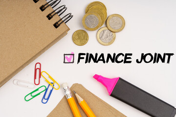 On a white background notepads, paper clips, coins, pencils and the inscription - FINANCE JOINT