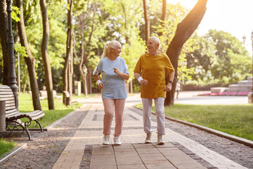 Obraz premium Happy mature woman with husband run along road in picturesque park