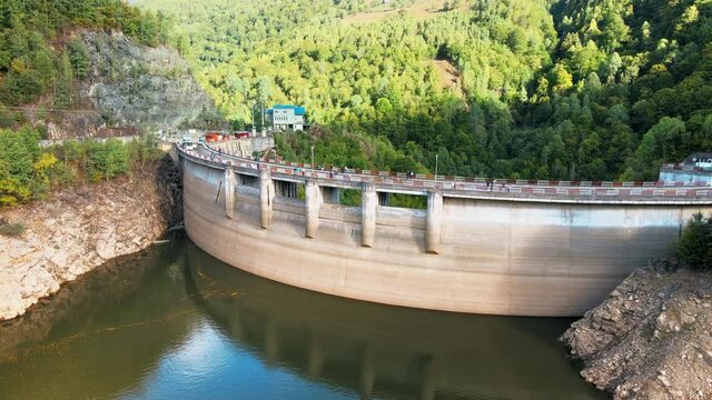 Aerial drone view of a Dam at the Taul Bistra lake in Romania. Carpathian mountains, hills with lush forest, multiple visitors